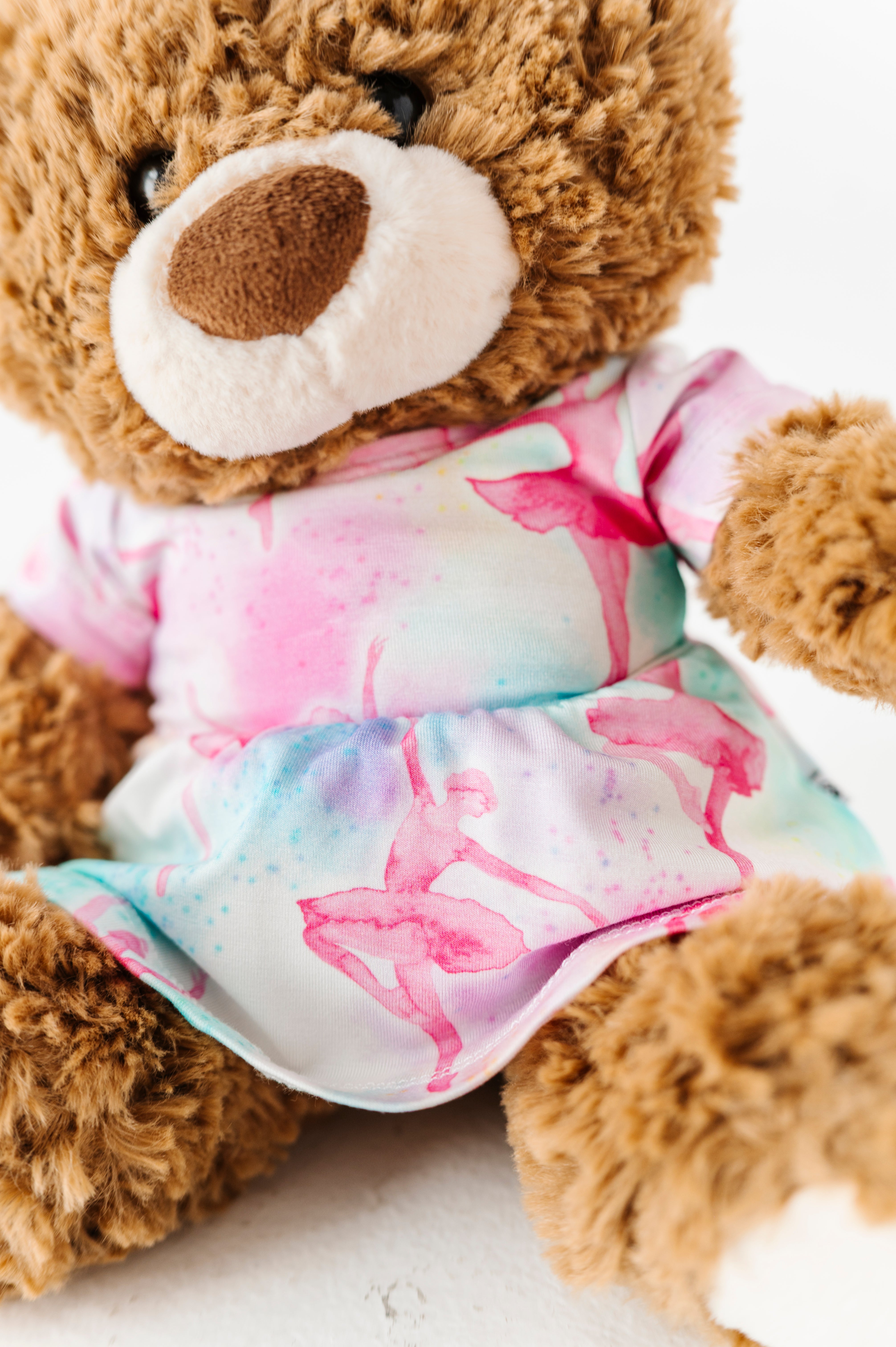 Brown teddy bear wearing a bamboo dress featuring pastel watercolor ballet dancers